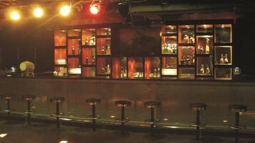 Un bar con varios taburetes y estantes llenos de botellas.