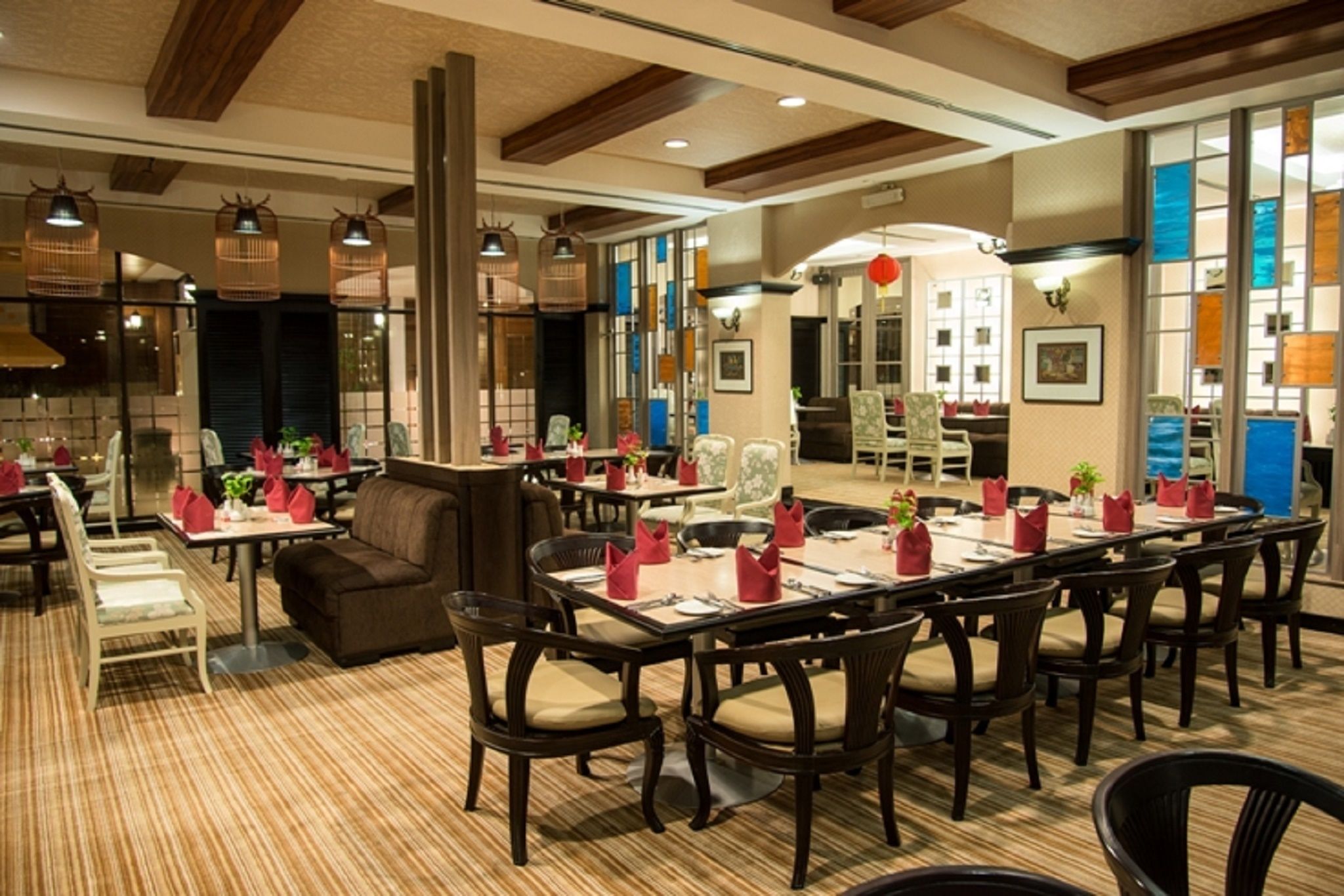 A restaurant with multiple dining tables, chairs, and a mix of wooden and upholstered seating.