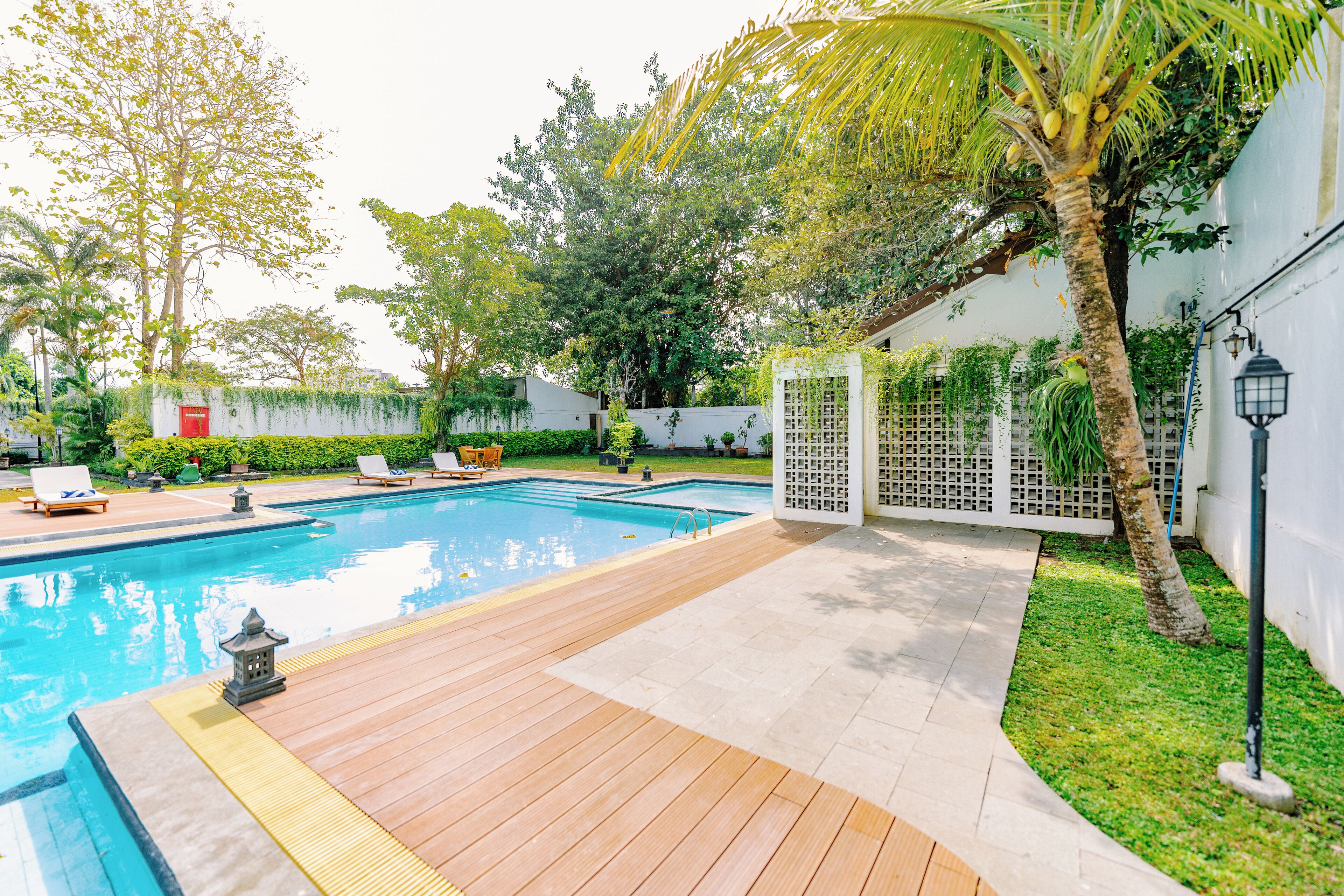 Piscina con cubierta de madera, sillas de descanso y un pequeño farol.