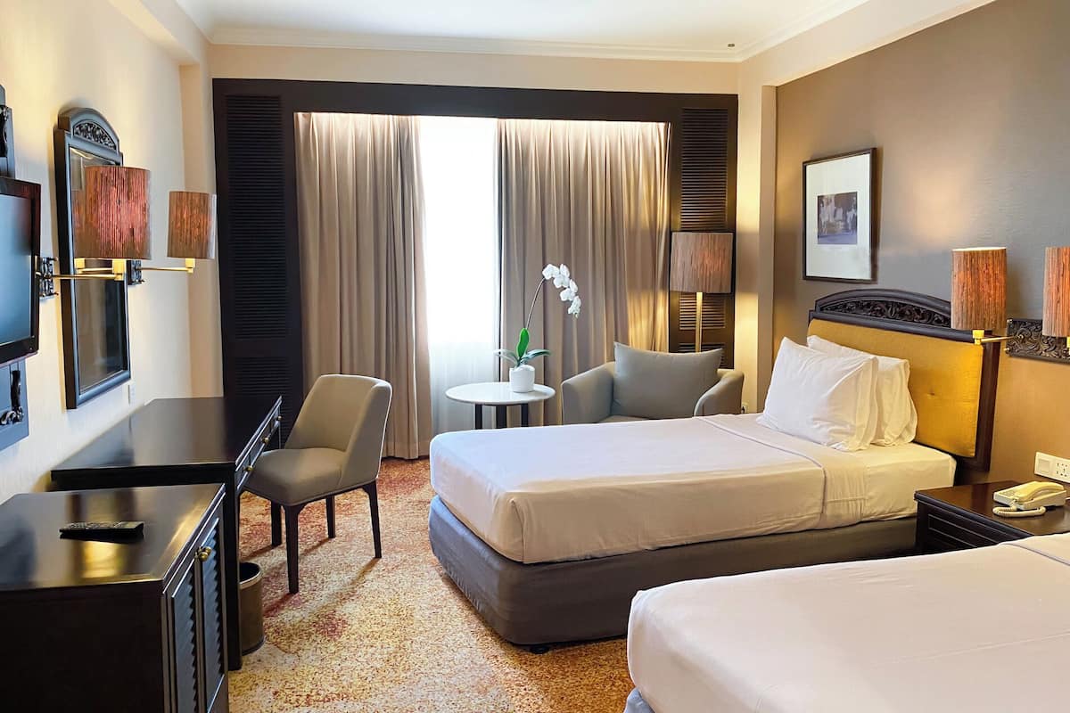 Een hotelkamer met een bed, een bureau, een stoel, een klein tafeltje en een televisie.