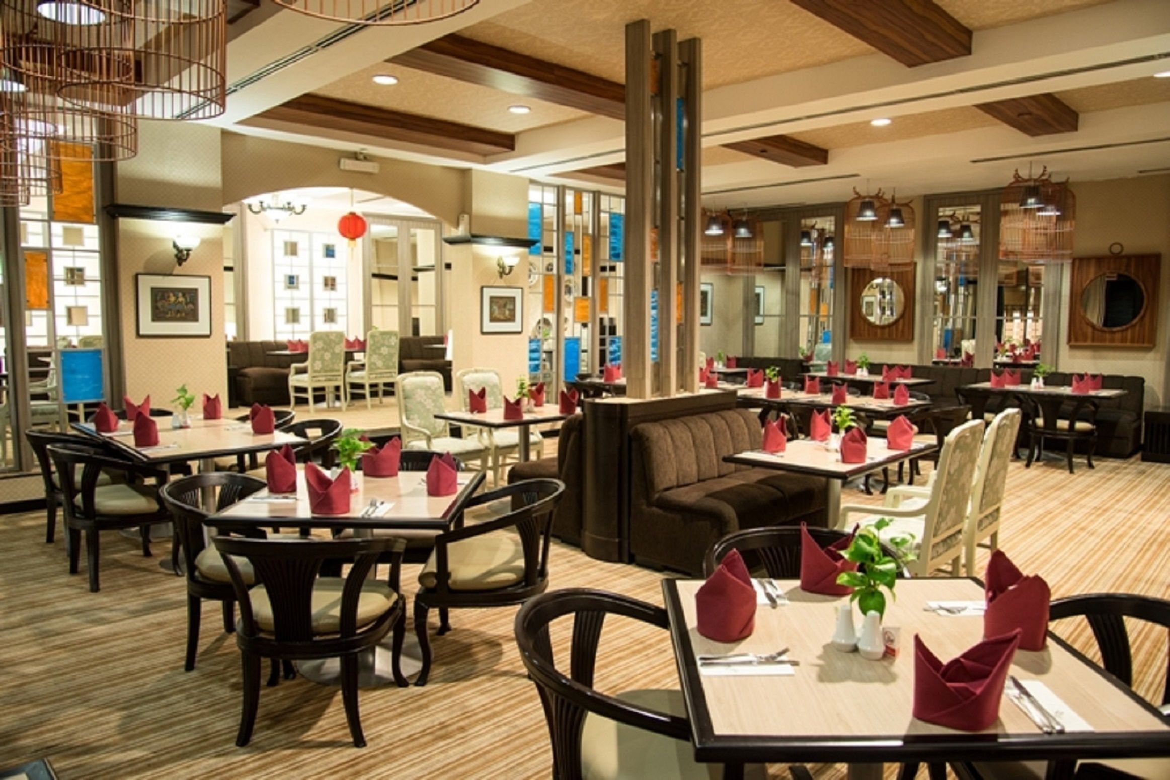 Un restaurante espacioso con varias áreas de comedor, incluyendo cabinas y mesas, además de una zona central con sofás.