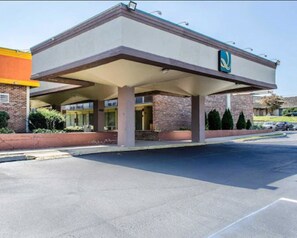 A hotel with a covered parking area, a brick facade, and a sign with a stylized 'N' logo. - Quality Inn & Suites York East (York)