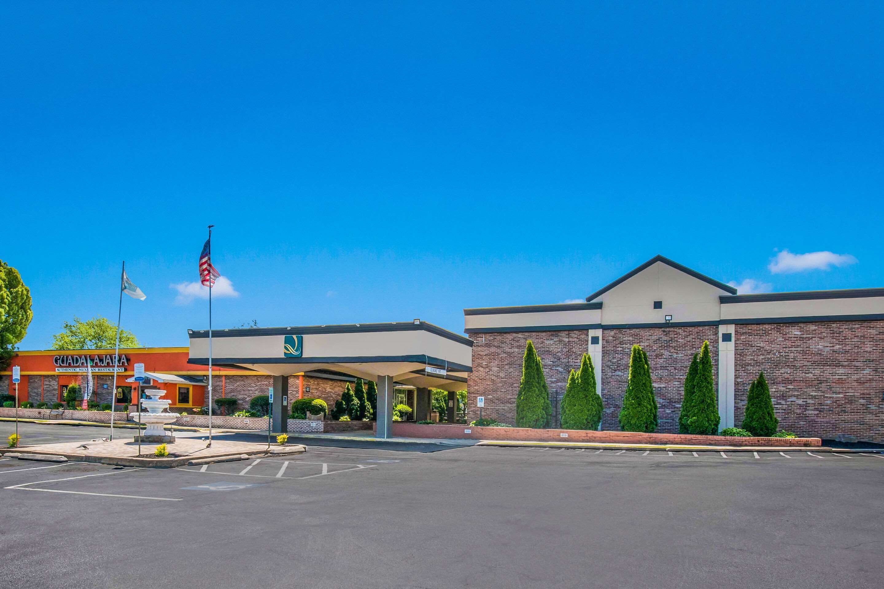 A commercial building with a parking lot, a fountain, and a flagpole.