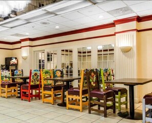 A restaurant with multiple tables and chairs, each with colorful artwork. - Quality Inn & Suites York East (York)
