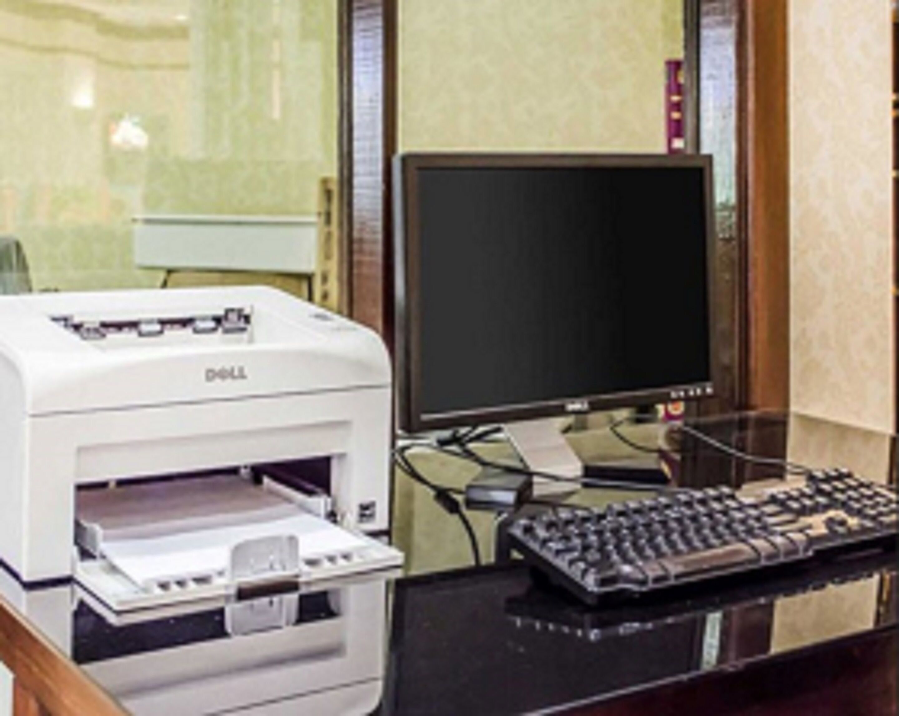 A Dell printer on a desk with a keyboard and a monitor.
