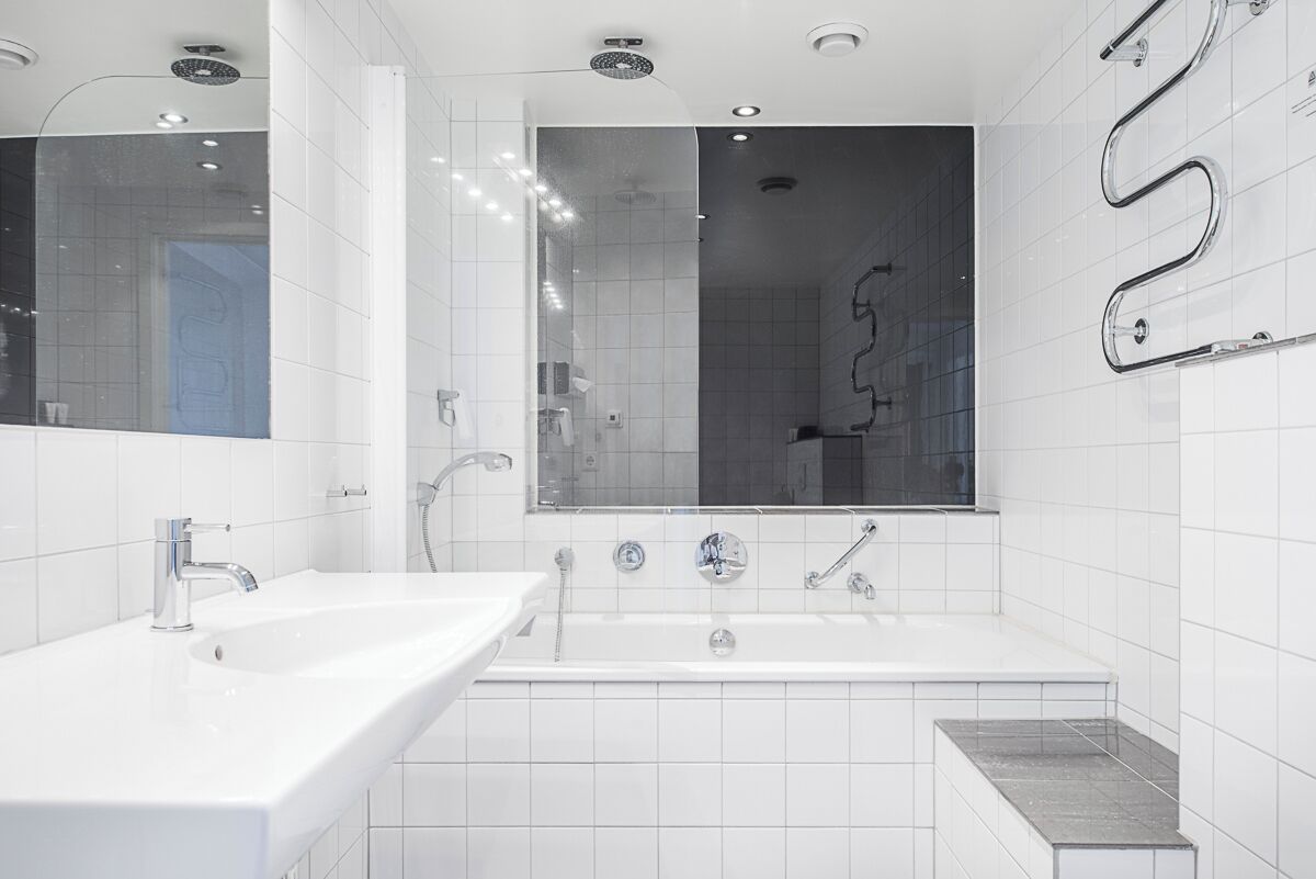 A modern bathroom with a white sink, a large mirror, and a bathtub.