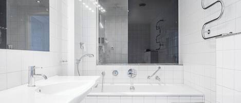 A modern bathroom with a white sink, a large mirror, and a bathtub.