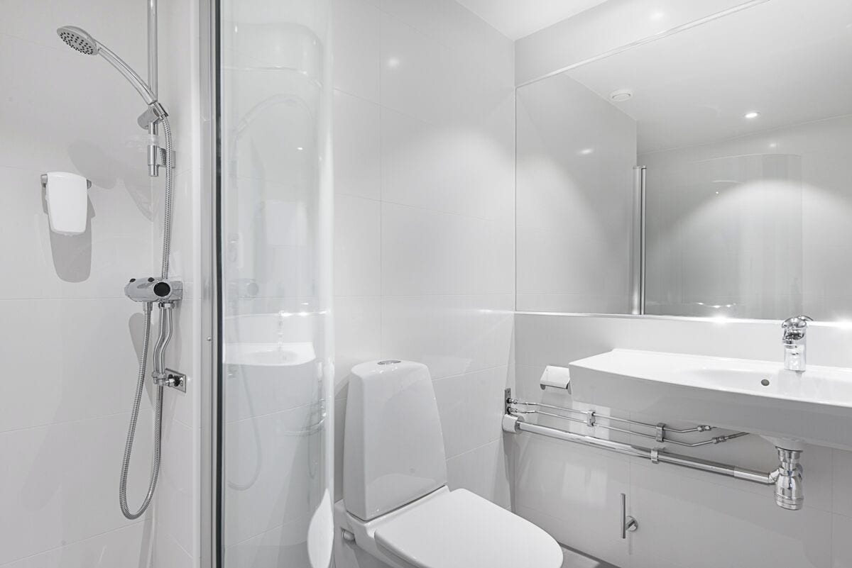 Ein modernes Badezimmer mit Duschkabine aus Glas, einer weißen Toilette und einem Waschbecken mit Handtuchhalter.