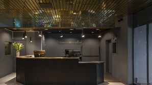 A modern hotel reception desk with a dark counter, overhead lighting, and a sign reading "Quality Hotel Grand". - ProfilHotels Grand Kristianstad (Kristianstad)
