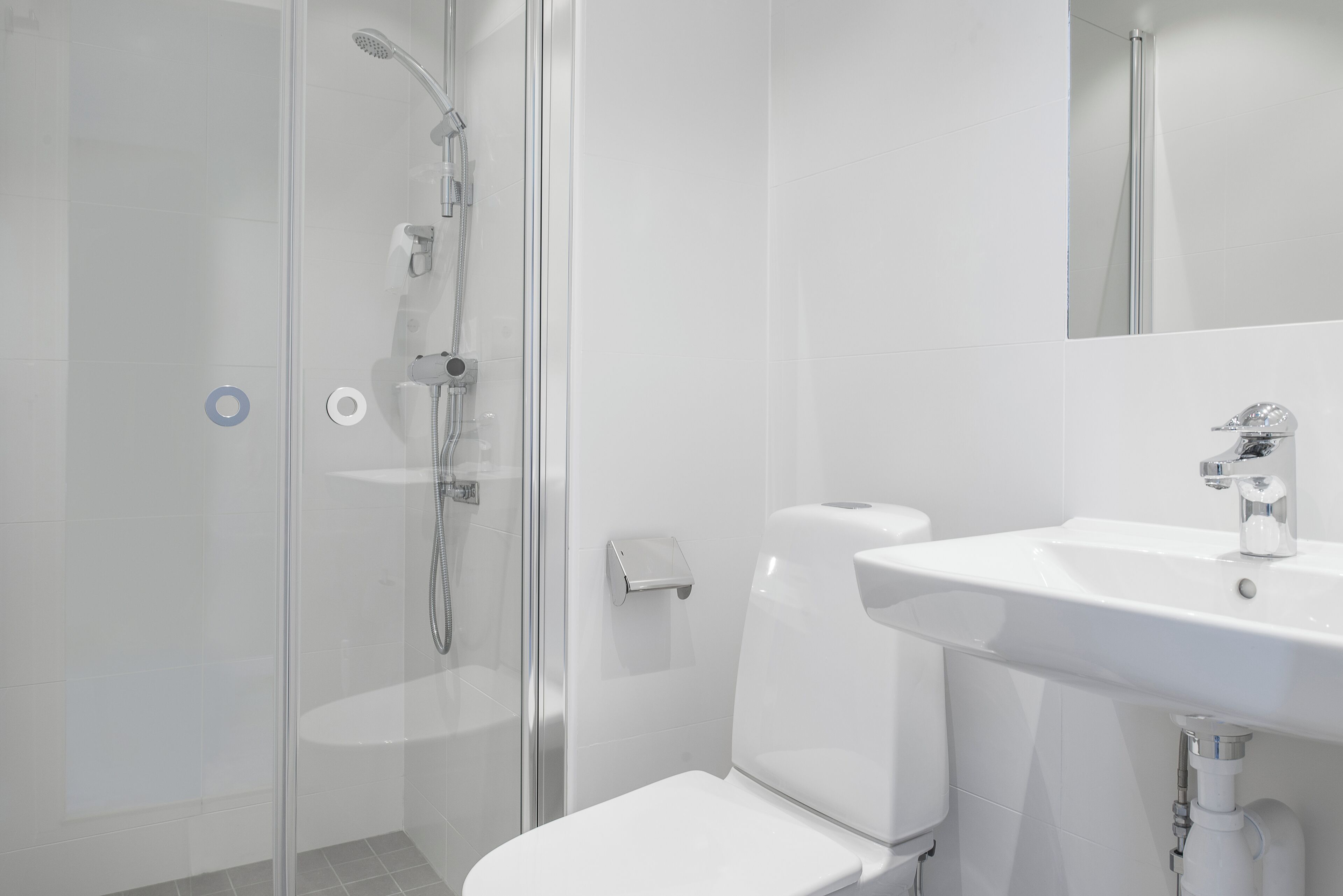 Ein modernes Badezimmer mit Duschkabine aus Glas, einer weißen Toilette und einem Waschbecken mit Spiegel.