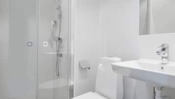 Ein modernes Badezimmer mit Duschkabine aus Glas, einer weißen Toilette und einem Waschbecken mit Spiegel.