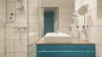 A modern bathroom with a glass shower enclosure, a white sink, and a blue vanity.