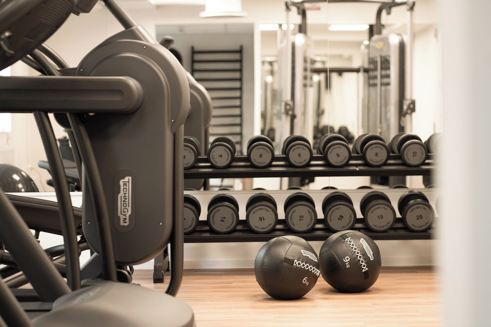 A gym with exercise equipment and dumbbells.