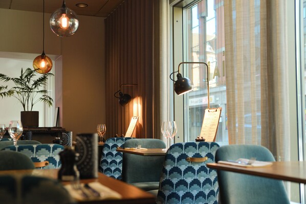 Enjoy a warm dining experience with a view of the city, surrounded by comfortable seating and elegant table settings.
