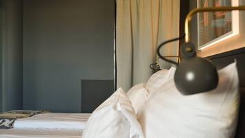 Quarto de hotel com cama, cabeceira, mesa de cabeceira e abajur.