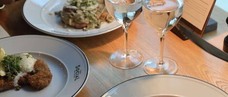 A dining table with plates of food, glasses of water, and a menu.