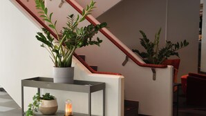 A staircase with red handrails, a potted plant on a shelf, and a candle on a table. - Quality Hotel the Mill (Malmö)