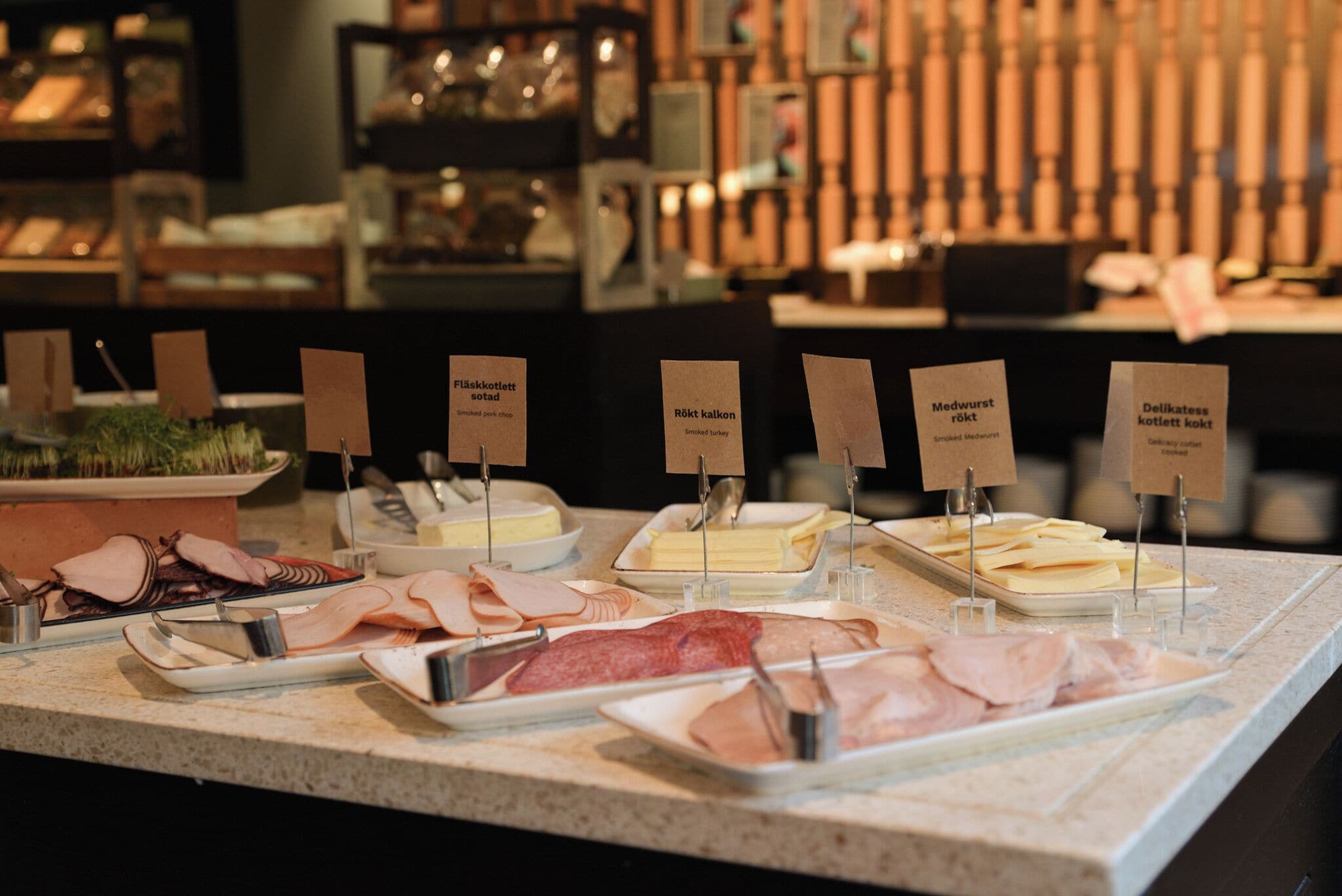 A buffet counter with various meat dishes labeled in a foreign language.