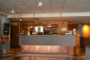 A hotel reception area with a counter, a sign that reads "You smile, I smile, you smile," and a floor mat with the same message.