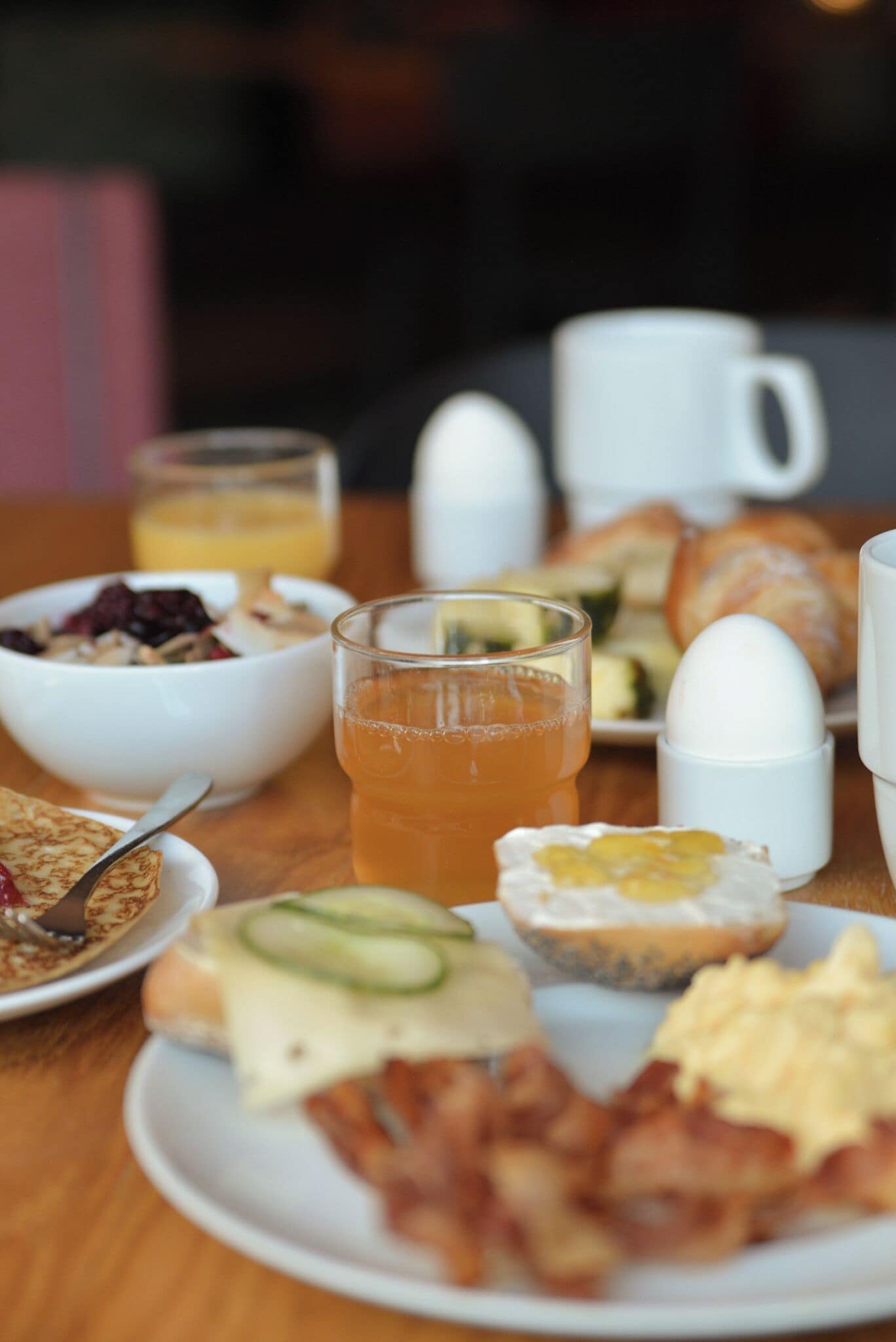 Una mesa de desayuno con diferentes platos, incluyendo tostadas, huevos y un vaso de jugo de naranja.