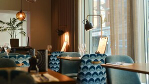A restaurant interior with patterned chairs, hanging pendant lights, and a view of the city through large windows. - Quality Hotel the Mill (Malmö)
