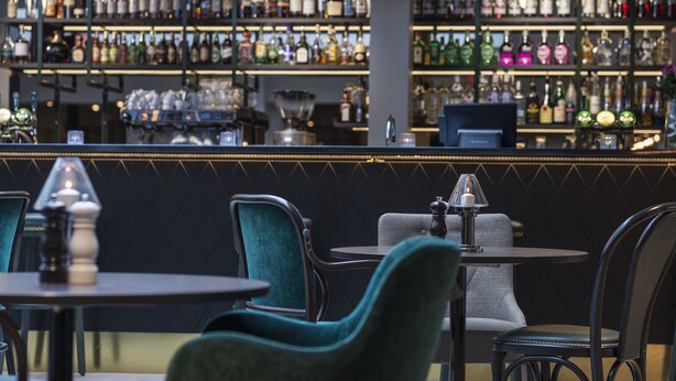 Eine Bar mit mehreren Regalen voller Spirituosenflaschen, einer Theke und Sitzgelegenheiten mit Tischen und Stühlen.