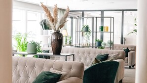 Ein stilvolles Wohnzimmer mit gepolsterten Sofas, einem Couchtisch und verschiedenen topfgestellten Pflanzen.