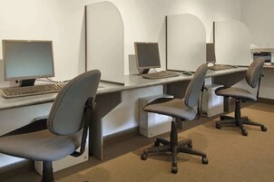 A row of office cubicles with computers, chairs, and a whiteboard.