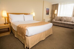A hotel room with a large bed, a sofa, two bedside lamps, and a framed picture on the wall.