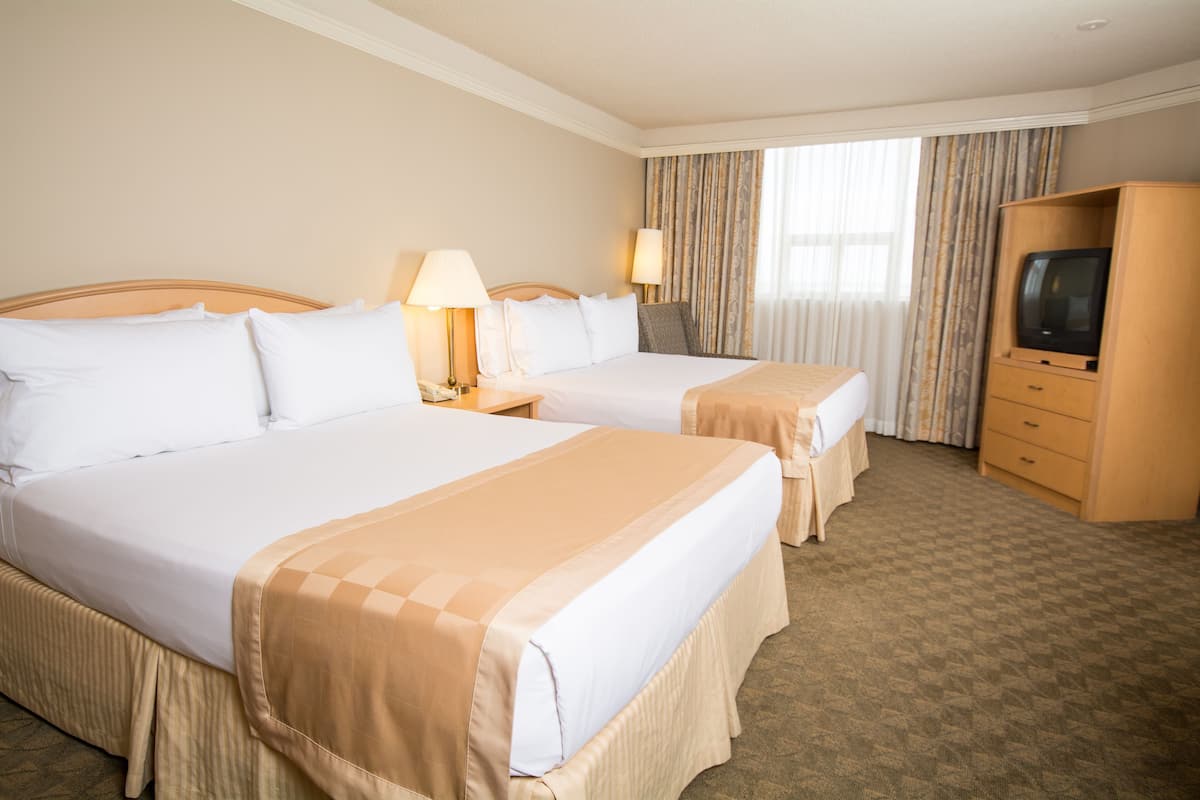 A hotel room with two beds, a TV, and a dresser.