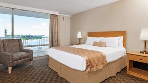 Une chambre d’hôtel avec un grand lit, une chaise, une table de chevet et une vue sur un immeuble par une grande fenêtre.