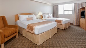 Une chambre d’hôtel avec deux lits, un canapé, une télévision et une fenêtre avec des rideaux.