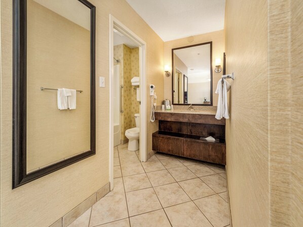A hotel bathroom with a walk-in shower, a toilet, a sink with a vanity, and a large mirror.