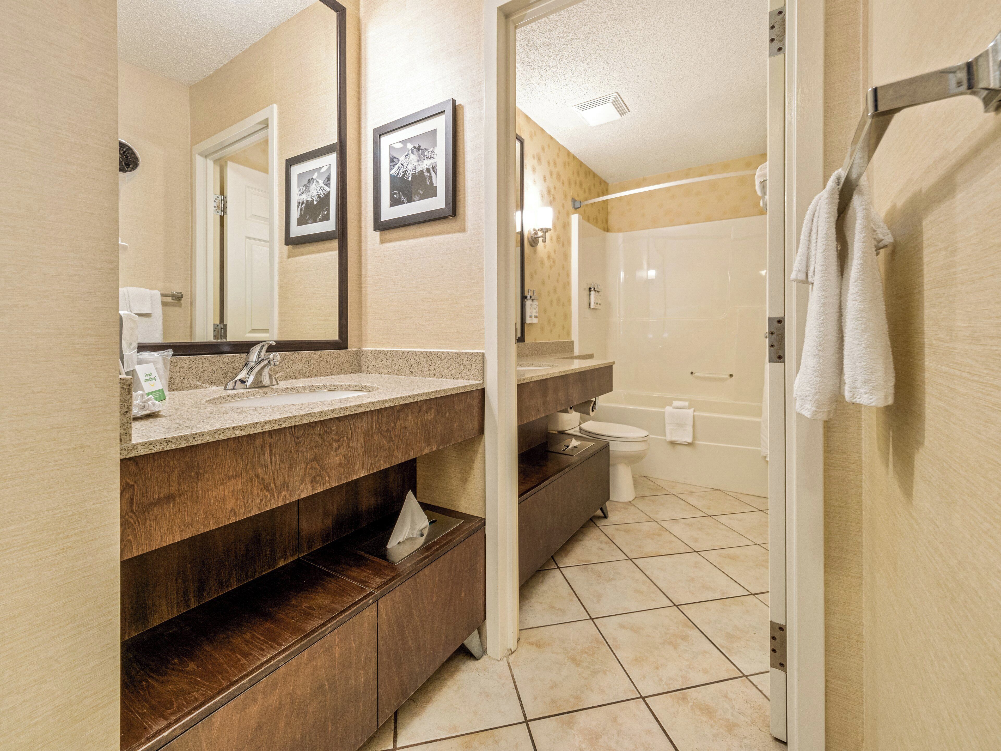 A bathroom with a wooden vanity, a sink, a mirror, a toilet, and a bathtub.