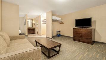 Habitación de hotel con sofá, televisión, cómoda y baño a la vista.
