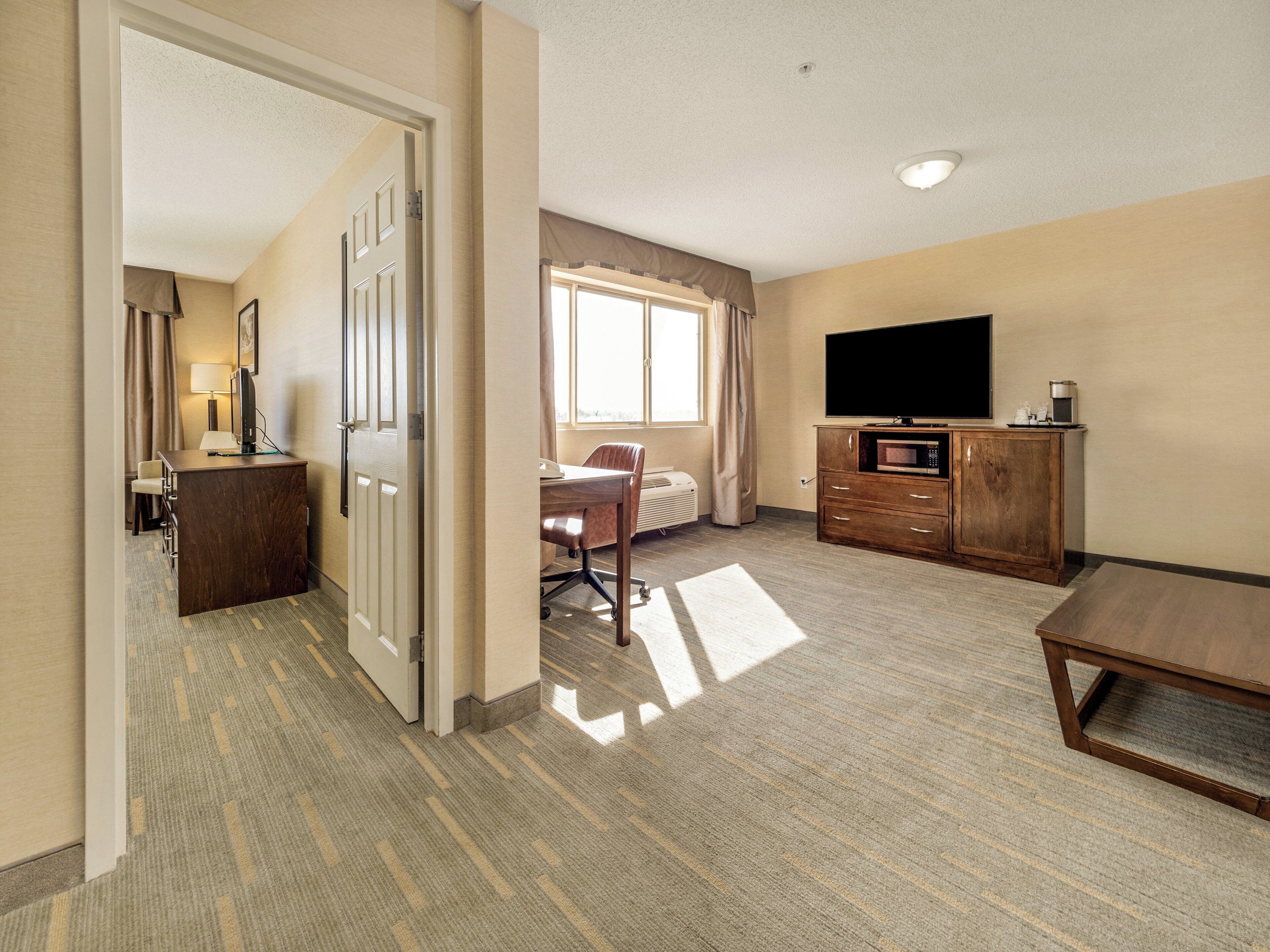 Habitación de hotel con escritorio, silla, televisor y un mueble bajo.