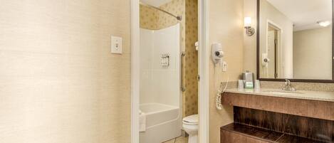A bathroom with a bathtub, toilet, and a vanity with a mirror.