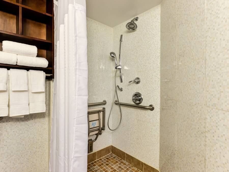 A shower with a handheld showerhead, a handheld showerhead, and a handheld showerhead.