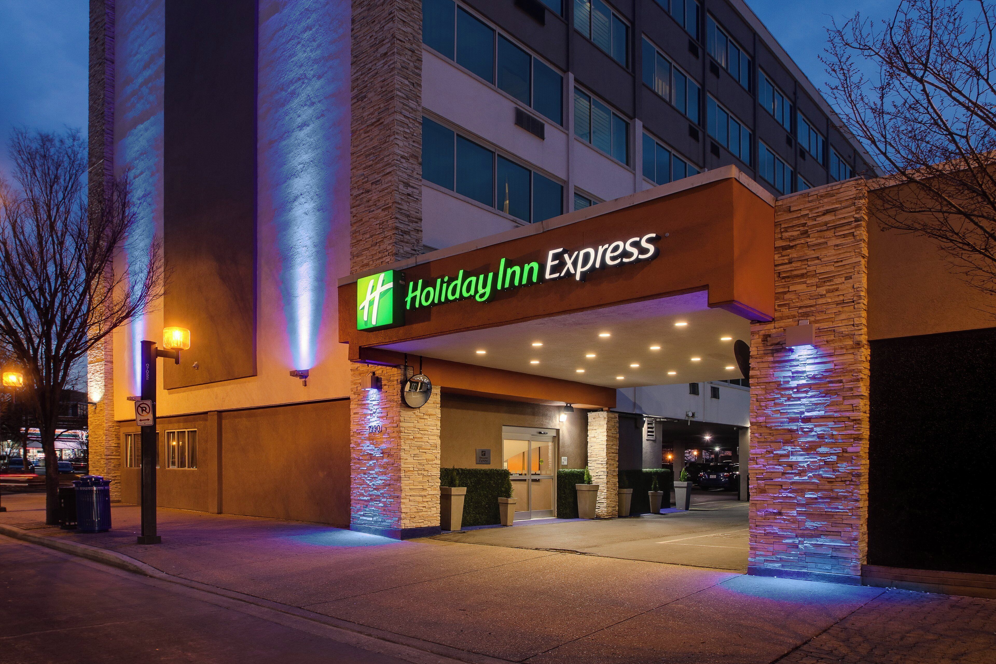 L’extérieur d’un hôtel Holiday Inn Express, doté d’un design moderne, se caractérise par une entrée imposante et une enseigne lumineuse bien visible.