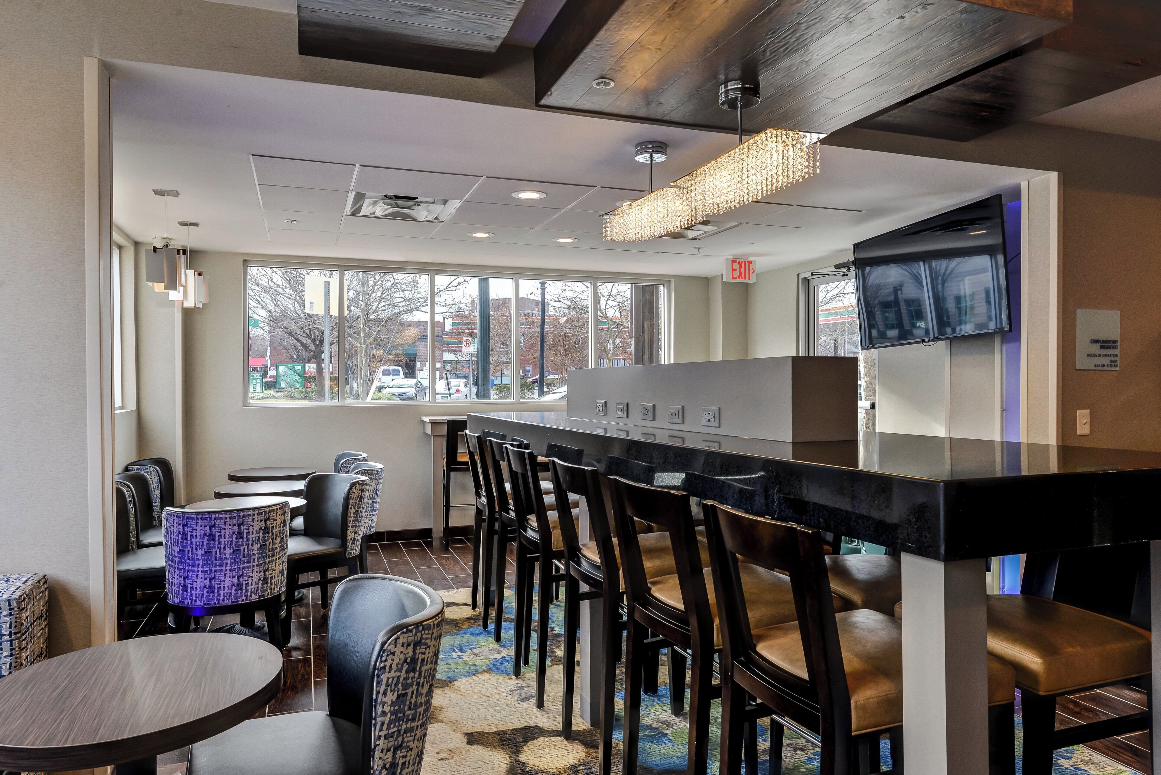 A restaurant with a bar, seating area, and large windows offering a view of the street.
