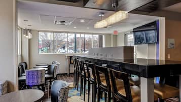 A restaurant with a bar, seating area, and large windows offering a view of the street.