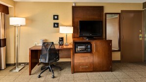 A hotel room with a wooden desk, a flat-screen TV, a microwave, a coffee maker, a chair, and a door. - Holiday Inn Express Washington DC N-Silver Spring by IHG (Silver Spring)