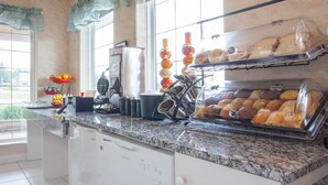 Uma cozinha com bancada de granito, cafeteira, torradeira e suporte para pão.