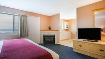 Habitación de hotel con cama, chimenea, televisor, cómoda y vista panorámica de la ciudad.