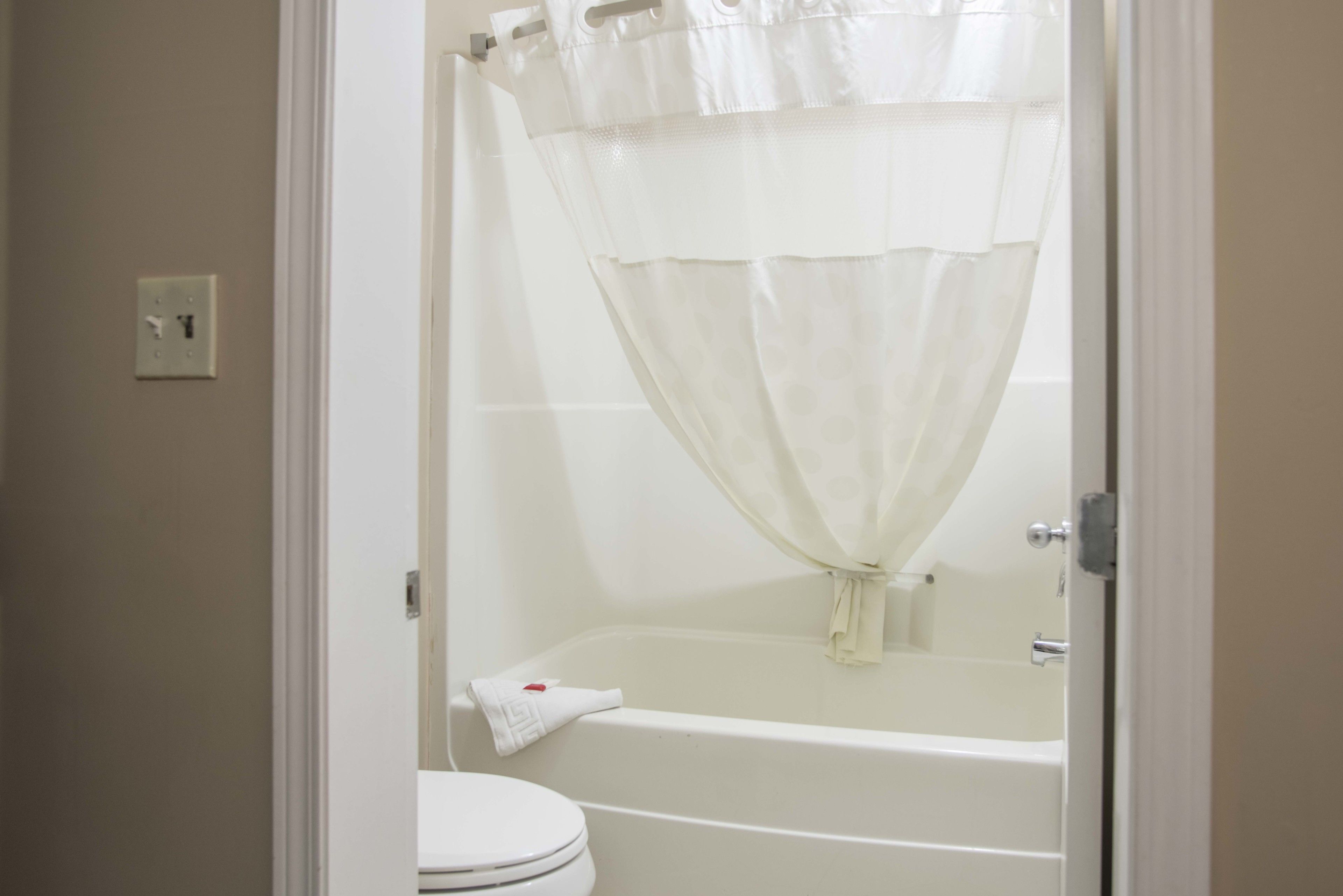 Un baño con bañera, inodoro y cortina de ducha.