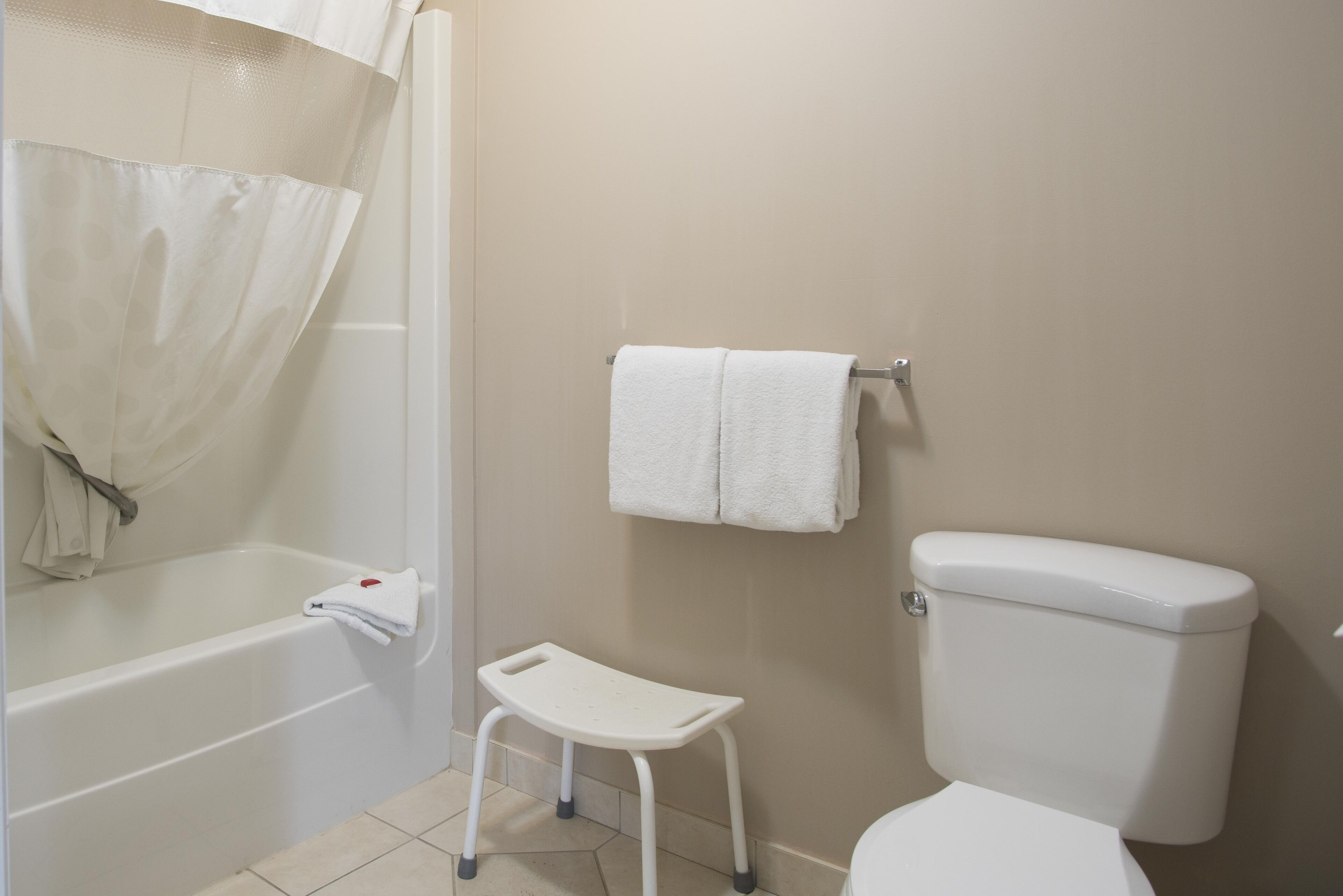 Un bagno con una vasca, uno sgabello, un water e un portasciugamani.