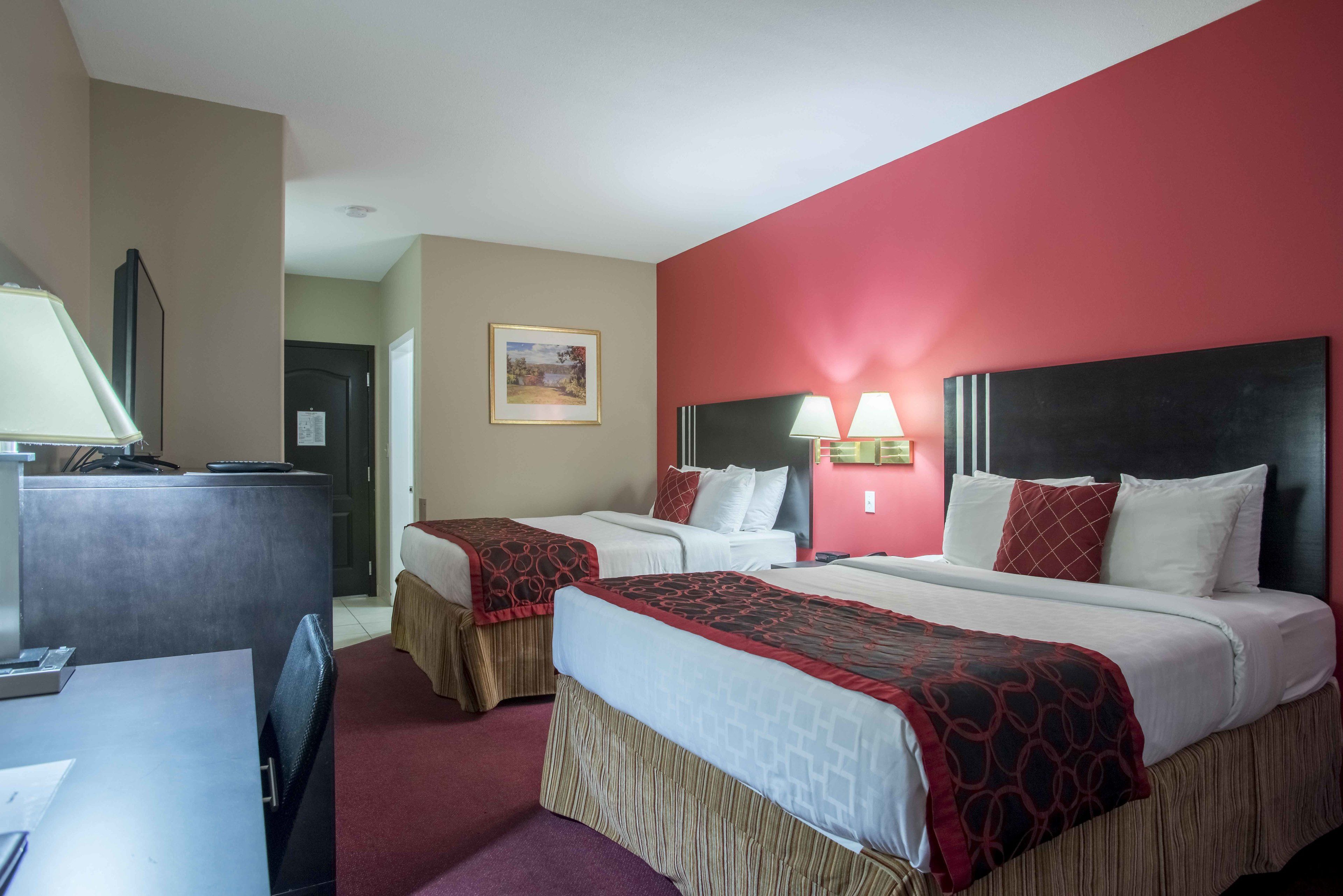A hotel room with two beds, a desk, and a TV.