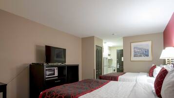 Een hotelkamer met twee bedden, een televisie, een magnetron en een ingelijste foto aan de muur.