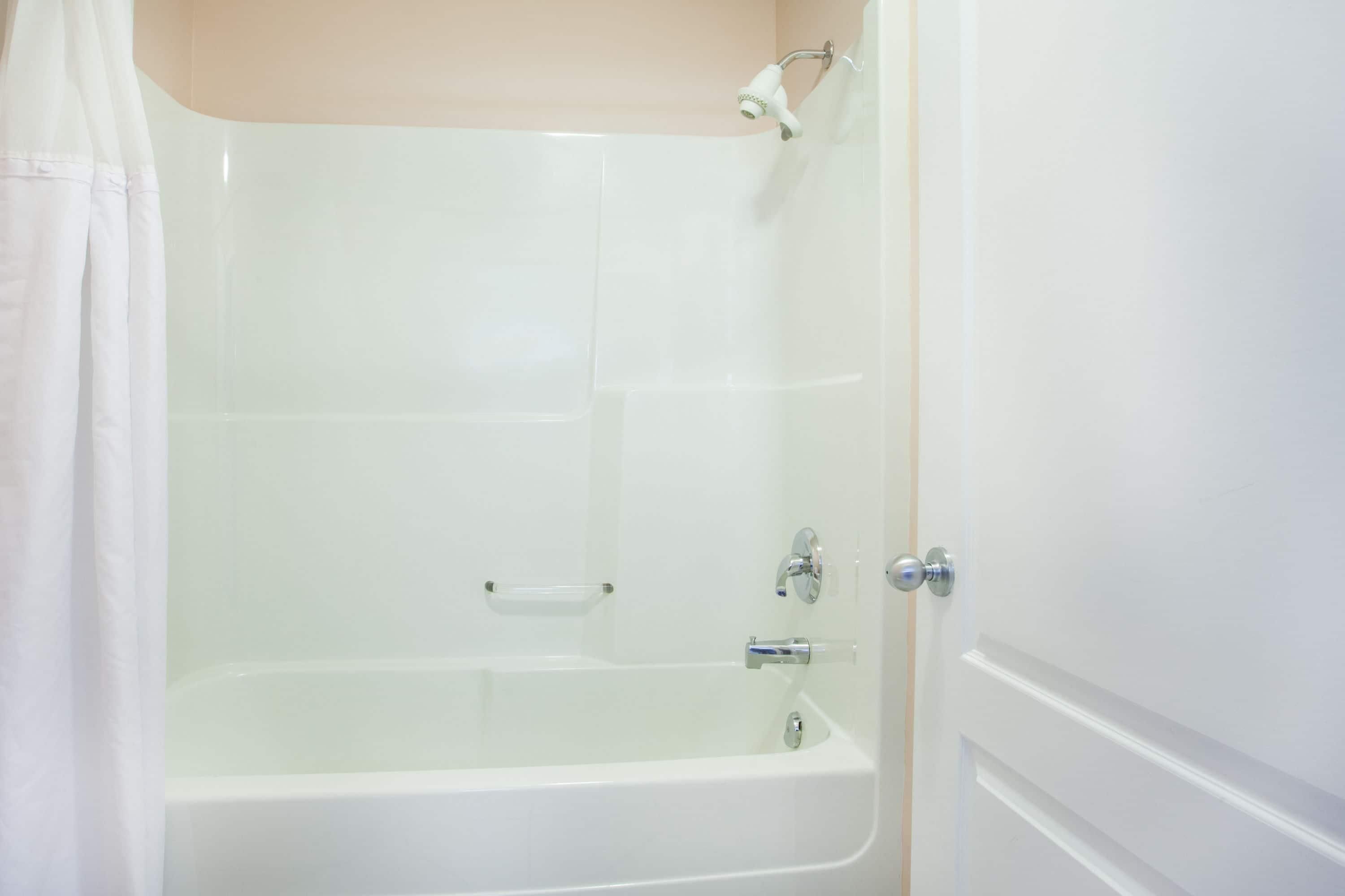 A white bathtub with a showerhead, a glass door, and a towel rack.