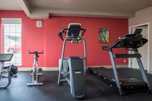 Un gimnasio con cintas de correr, una bicicleta estática y un banco de pesas.